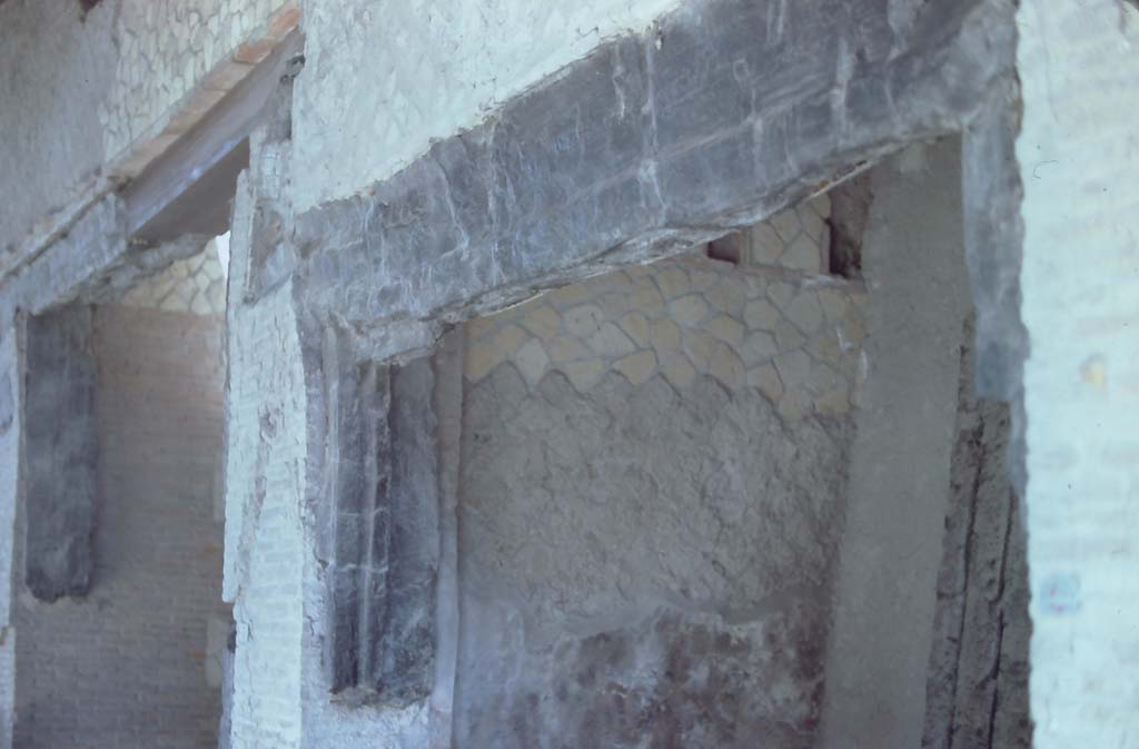 Decumanus Maximus, Herculaneum. 7th August 1976. 
Looking towards west wall of shop numbered 4, and detail of carbonised wood from above doorway.
On the left, is the carbonised wood above doorway numbered 3.
Photo courtesy of Rick Bauer, from Dr George Fay’s slides collection.
