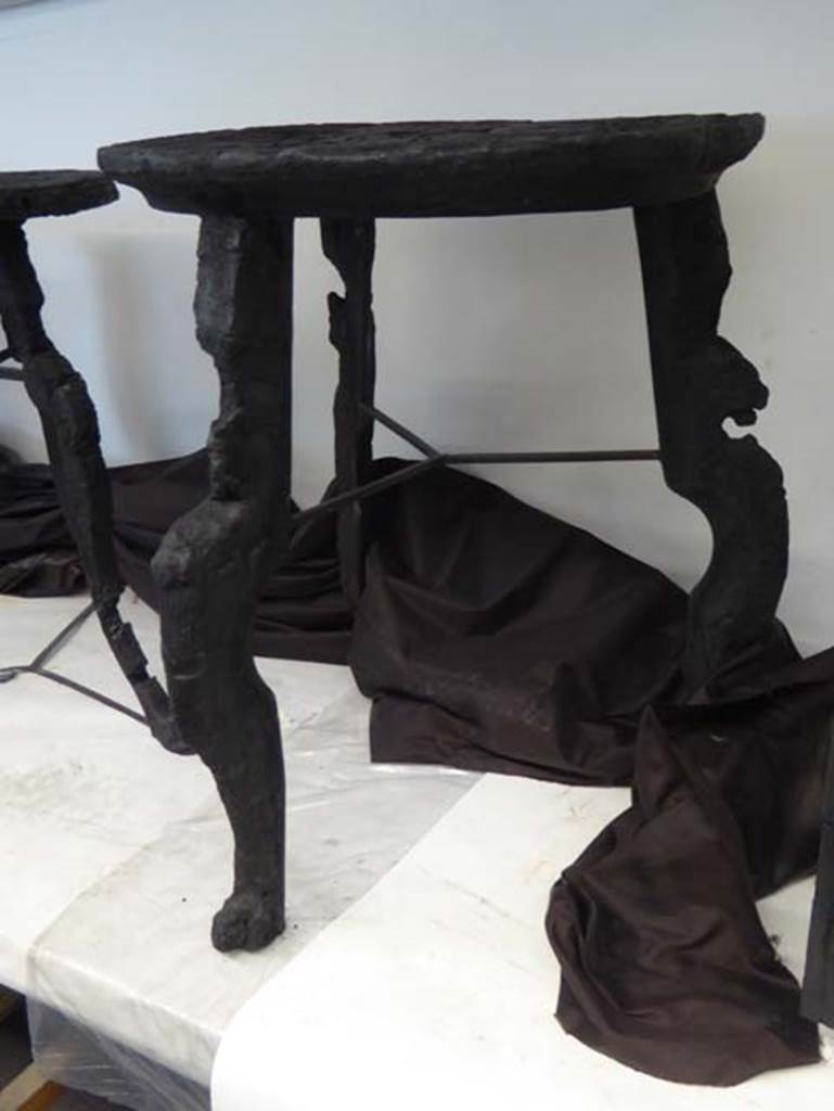 IV.1/2 Herculaneum, September 2016. 
Carbonised wooden table with circular top and three legs decorated with griffins, perhaps from Exedra 9. Photo courtesy of Michael Binns.
See Camardo, D, and Notomista, M, eds. (2017). Ercolano: 1927-1961. L’impresa archeologico di Amedeo Maiuri e l’esperimento della citta museo. Rome, L’Erma di Bretschneider, (p.196, fig 2, Scheda 9).
See De Carolis, E. (2007). Il mobile a Pompei ed Ercolano, letti tavoli sedie e armadi. Rome, “L’ERMA” de Bretsneider, (p.104) 
He also lists – See Mols, 1999, p.127-129, 170-181, Storie da un’eruzione, 2003, p.118, 1,41.
