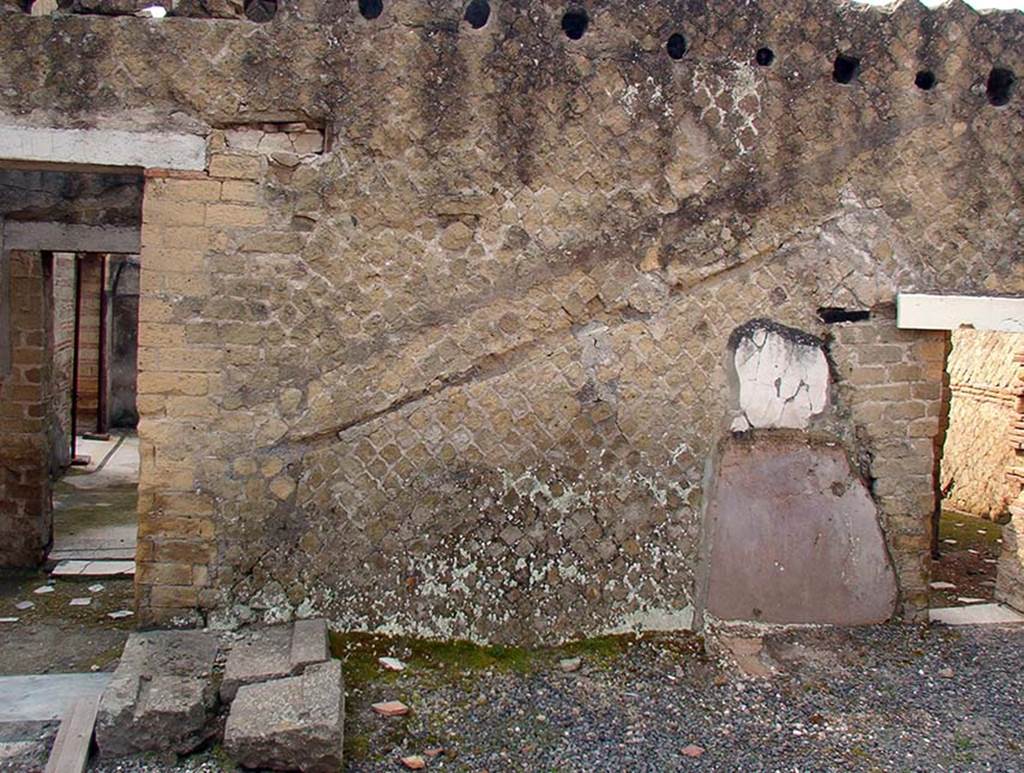 IV.1/2 Herculaneum. May 2019. Site of wooden stairs against south wall of peristyle, with remains of stone base, on left, and imprints of stairs on the wall. 
Photo courtesy of Domenico Camardo.
In 2006 excavations were carried out in this area. On the left are the stone steps, made from reused thresholds, that formed the base of the wooden staircase. 
Under them were the remains of the mosaic pavement that covered a beaten cocciopesto layer and a red tufa step belonging to a more ancient staircase.
This situation clearly indicates that initially all the cryptoporticus had been paved with cocciopesto.
After the original excavations, Maiuri had left the mud of the eruption below the carbonised wooden stairs. Over the years, the wooden stairs have been destroyed. 
On the right, under the stairs, was a small room, the site of a latrine which would have been accessible from corridor 20, through the doorway on the right.
This is shown here by the plaster on the wall and the cocciopesto tray partly visible in the floor.
See Domenico Camardo, Saggi nell’angolo sud-ovest del criptoportico (C), Rivista di Studi Pompeiani, XVII, 2006, (p. 117-18, fig. 16).

