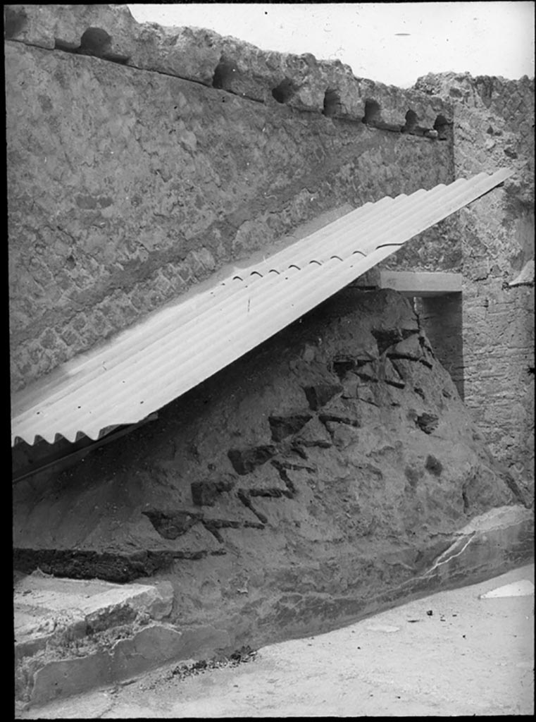 IV.1/2 Herculaneum. 1932. Photo by P. C. 
Stone base and remains of carbonised wooden stairs against south wall of peristyle.
Used with the permission of the Institute of Archaeology, University of Oxford. File name instarchbx92im003 Resource ID 41152.
See photo on University of Oxford HEIR database
