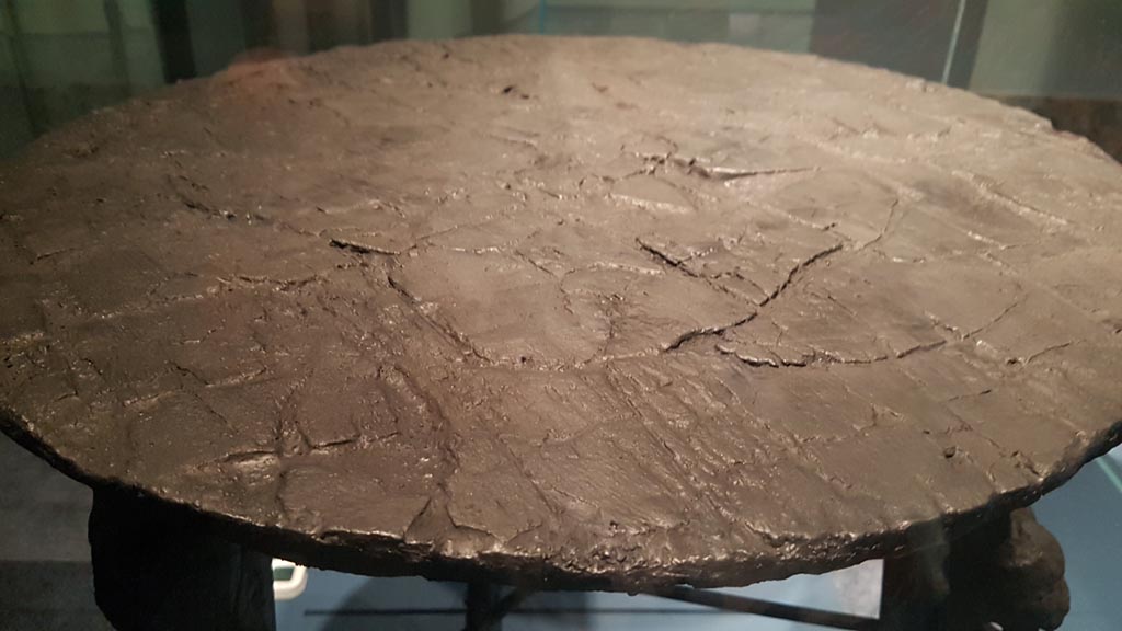 V.5 Herculaneum. August 2023. Detail of wooden top with carbonised wooden table with clawed legs. Photo courtesy of Maribel Velasco.
On display in exhibition entitled – “Materia. Il legno che non bruciò ad Ercolano”.  


