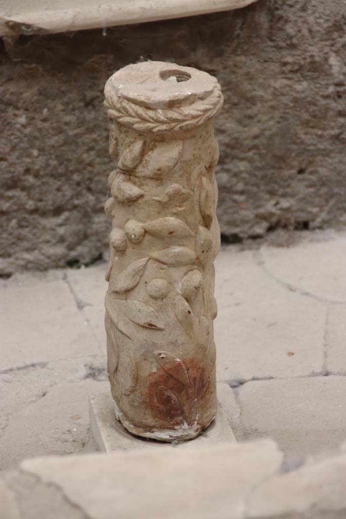 V.7 Herculaneum. September 2017. Column from between couches. Photo courtesy of Klaus Heese. 
According to Jashemski, an elegant column ornamented with ivy leaves and berries which would have held the fountain pipe, was between the couches.
Maiuri believed it would have once held the bowl of a fountain.

