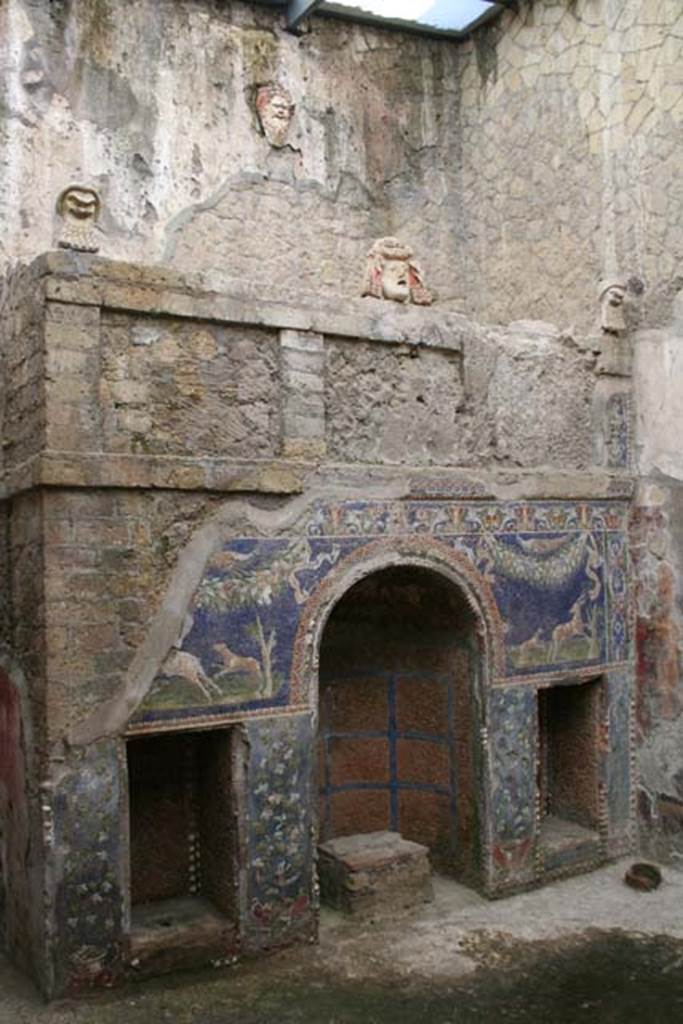 V 7, Herculaneum, March 2008. 
North wall with nymphaeum niche, theatrical masks, and tank that fed the fountain which is above the niche. 
Photo courtesy of Sera Baker.
