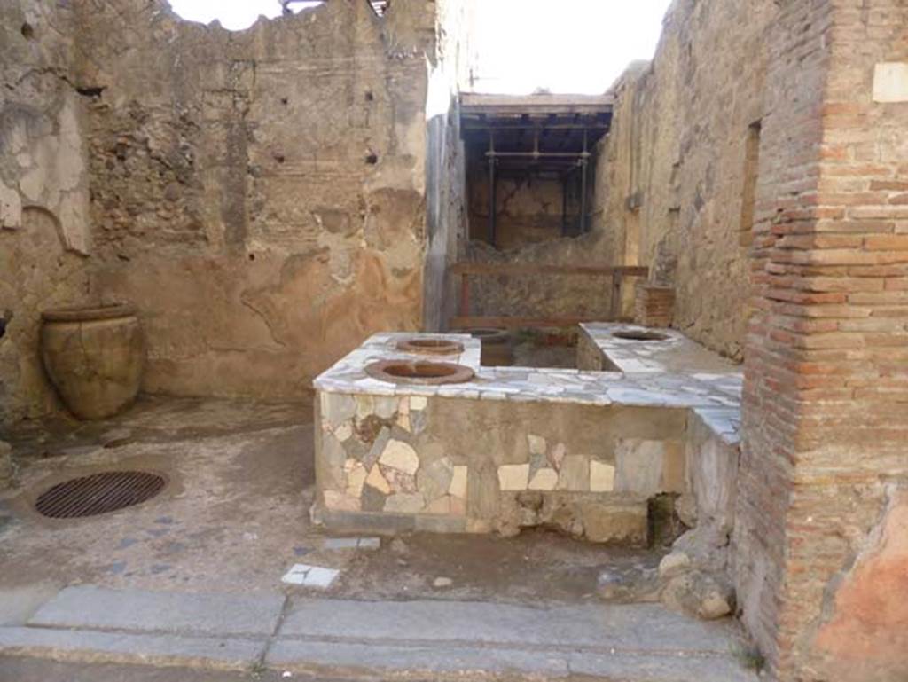 V.10, Herculaneum, September 2015. Looking south across counter in shop-room towards a rear room with side entrance doorway at V.9, on right.