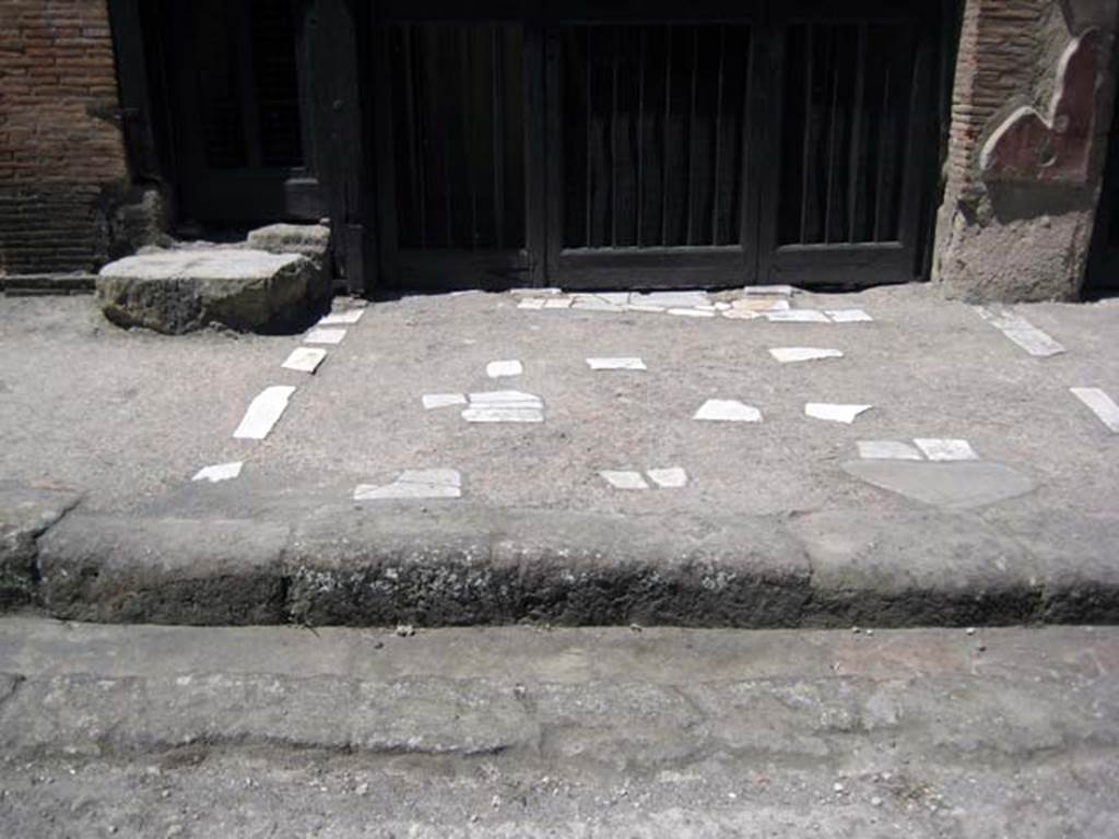 V.17 Herculaneum, June 2011. Pavement outside entrance to V.17, on right, and steps to upper floor at V.18, on left.
Photo courtesy of Sera Baker.
