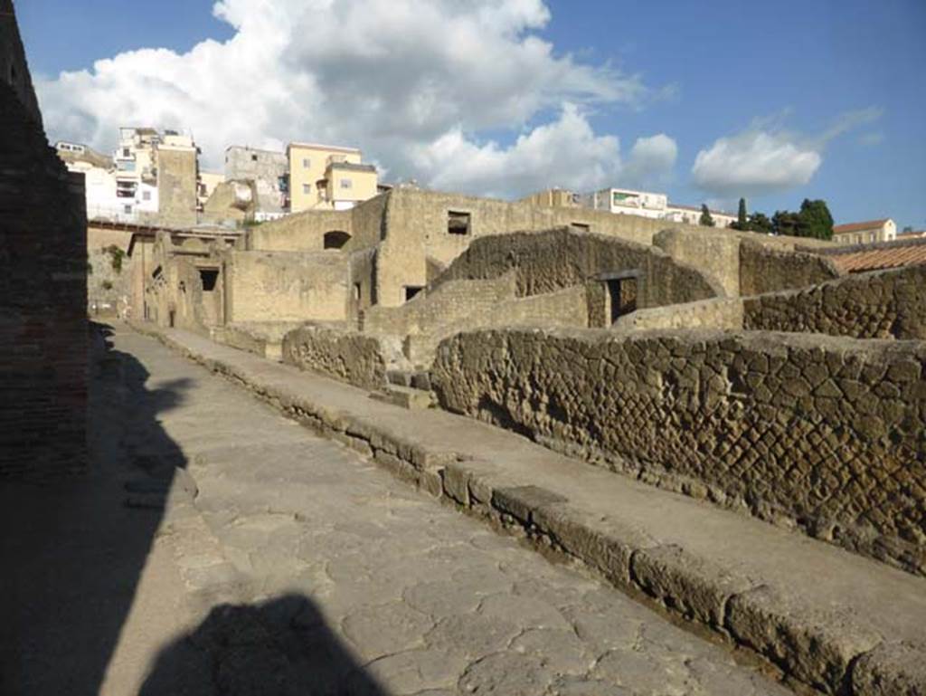 VI, Herculaneum, September 2015. Looking north-east towards east side of Cardo III Superiore, from junction with Decumanus Inferiore. On the west side of the roadway, between the shadows of the building, appears to be a round drain cover, see photo below.