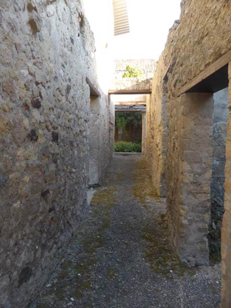 VI 26, Herculaneum, September 2015. Looking east along the long corridor towards peristyle, from rear entrance doorway. The doorway in the north wall, on the left, leads into the kitchen. The two doorways on the right lead into two rooms used as storerooms/cupboards in the services area.