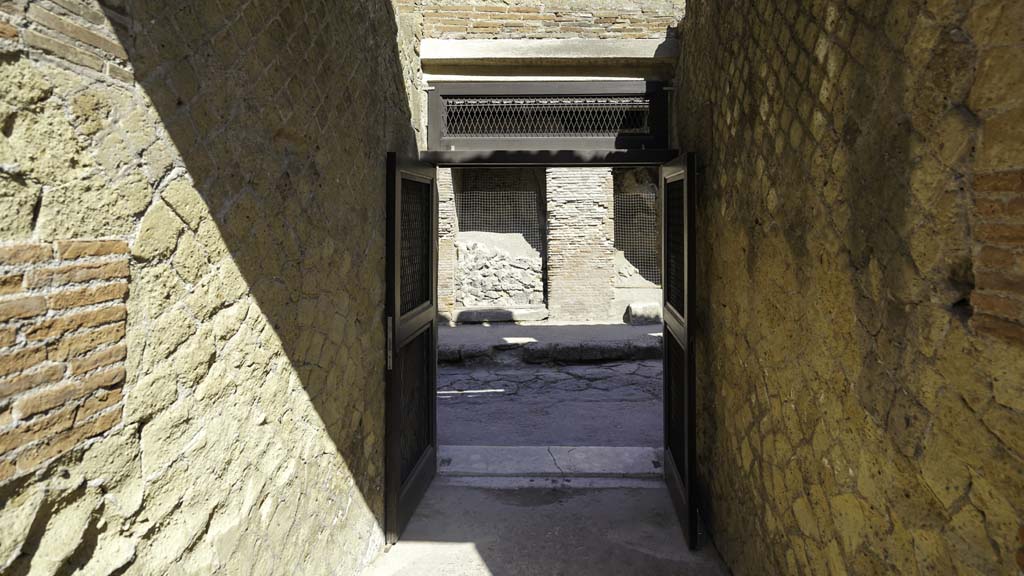 VI.29 Herculaneum. August 2021. 
Looking west through entrance corridor towards roadway in Cardo III. Photo courtesy of Robert Hanson.
