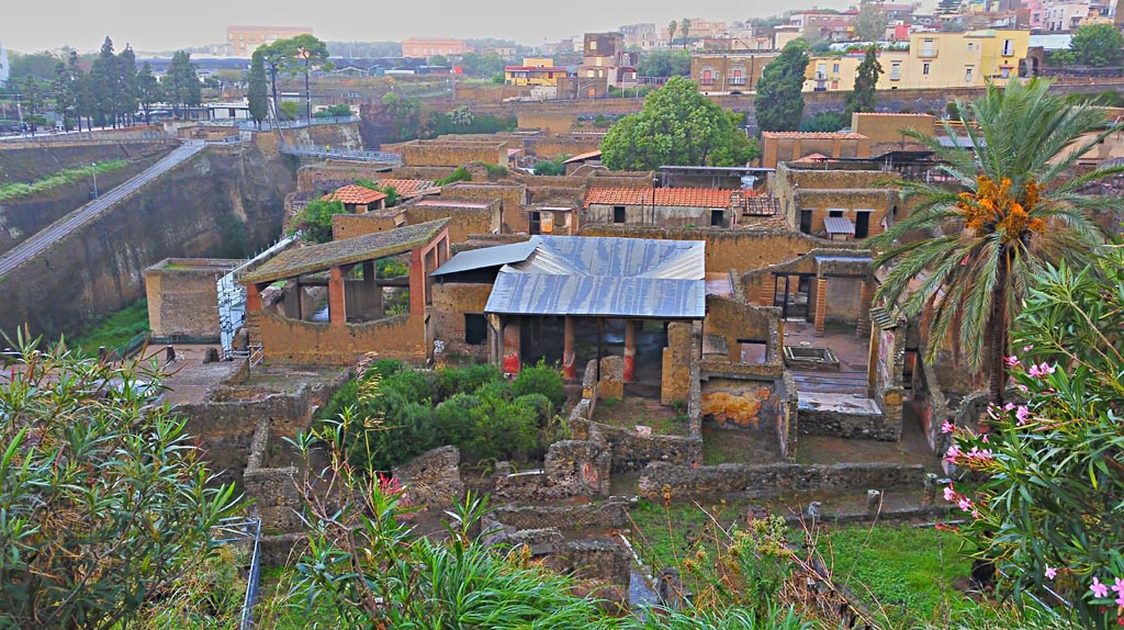 Ins. Or. I.1 Herculaneum. Photo taken between October 2014 and November 2019.
Looking west from access roadway towards re-roofed atrium and rear garden of the House of Gem, in centre. Photo courtesy of Giuseppe Ciaramella.
