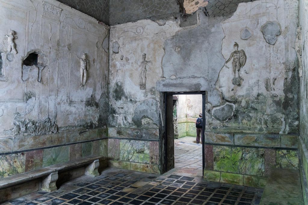 Herculaneum Suburban Baths. October 2023. 
Tepidarium, north-west corner and north wall with doorway into frigidarium. Photo courtesy of Johannes Eber. 
Decorative stucco warriors on white stucco panels were set into the walls of the tepidarium.
In this room were eight large white rectangular panels.
On seven of these panels were depicted stucco warriors (six showed warriors carrying spears, the seventh carrying a sword).
On the eighth panel were two stucco flying cupids carrying baskets of fruit and garlands.


