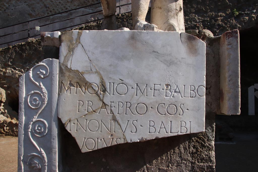 Herculaneum, October 2022. Inscription below statue of Marcus Nonius Balbus. Photo courtesy of Klaus Heese.
The statue of Balbo on the terrace itself stands on a marble foundation in front of the altar. It was erected by his freed slave M. Nonius Volusianus. 
According to the Epigraphic Database Roma this read

M(arco) Nonio M(arci) f(ilio) Balbo
prae(tori) pro co(n)s(uli)
M(arcus) Nonius Balbi
[l(ibertus)] Volusian[us]
- - - - - - (?)

According to Cooley this translates as 
To Marcus Nonius Balbus, son of Marcus, praetor, proconsul, Marcus Nonius Volusius [. . .].      [AE (1980) 249]
See Cooley, A. and M.G.L., 2014. Pompeii and Herculaneum: A Sourcebook. London: Routledge, F105b, p. 191.
