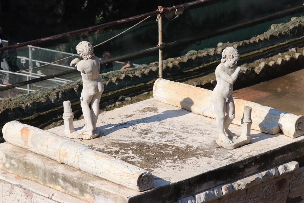 Herculaneum, October 2022. 
On the top of the altar stand two marble statues of sleeping funeral figures which would have been leaning on torches, but which are now broken. 
One of the two statues shows considerable traces of red-lead colour on their head of hair.  Photo courtesy of Klaus Heese.

