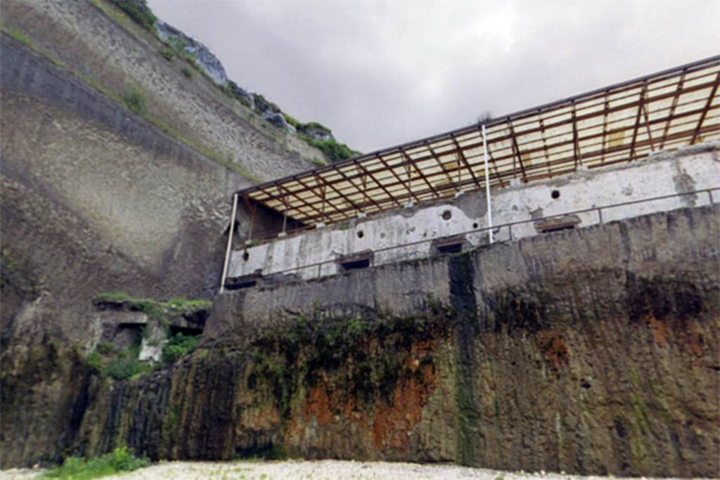 Villa dei Papiri, Herculaneum. 2004. The remains (left) of an apsidal/bow window on the second lower level.
The floor of first lower level of the basis villae is indicated by a string course on the façade of the Villa (height 24 cm; depth 26 cm), which suggests the presence of a further level.
During the Infratecna Excavation (1996-8), a structure protruding in respect to the front of the basis villae was discovered at the west end of the façade.
This apsidal or at least curvilinear avant-corps is marked by a series of large windows (1.75 m wide; 1.40 m high).
The avant-corps was therefore an imposing and airy 5.50 m high bow window structure.
It was furnished with ten windows arranged on two levels, all of which were bolted at the time of the eruption.
Inside the bay windows the space is still almost entirely filled up with volcanic material.
See Esposito D. and Guidobaldi M., 2010. New Archaeological Research at the Villa of the Papyri, in the Villa of the Papyri at Herculaneum. Berlin: De Gruyter, p. 41-2, fig. 32, notes 62-3.