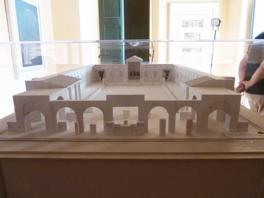 Herculaneum, Augusteum. September 2015. Augusteum model in Palazzo Reale showing locations of statues and paintings.
The Basilica was a large marble paved piazza, bordered by porticoes on all sides, and with a square exedra in the middle of the rear wall and an apse in each corner of the rear wall.
In the square exedra, at the rear centre in this model, were (left to right as seen here);
   The statue of the sitting Augustus (MANN 6040) 
   The standing breast-plated Titus, centre, (MANN 6059) 
   The statue of the sitting Claudius (MANN 6056).
In the apse, left rear corner in this model, were the paintings of; 
   The liberation of the Athenian children at the hands of Theseus (MANN 9049)
   The musical education of Olympus by Marsyas (MANN 9151)
   In front of these was a bronze statue of Augustus (MANN 5595).
In the apse, right rear corner in this model, were the paintings of; 
   The recognising of Telephus by Hercules (MANN 9008).
   The musical education of Achilles by Chiron (MANN 9109).
   In front of these was a bronze statue of Claudius as a heroic nude (MANN 5593).
Somewhere in the decoration of the side porticoes belonged a fresco of the life and labours of Hercules, and a panel with Medea (MANN 8976)
In the left portico were a bronze statue of Livia and a bronze statue of a priestess of Isis.
Many other statues of the Julio-Claudian dynasty and the Flavian dynasty were also found.
There is still much debate about the actual locations of items found.
