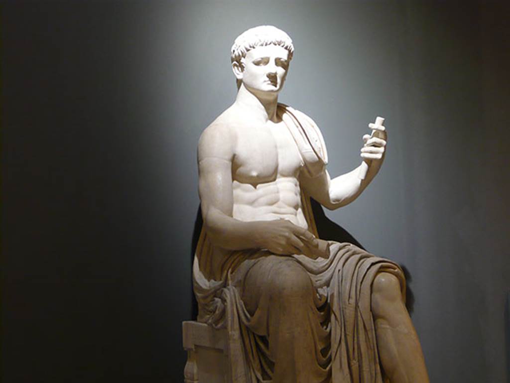 Herculaneum Augusteum. Square exedra. Statue of a seated Claudius. 
Now in Naples Archaeological Museum. Inventory number 6056.
According to the information board on site, the statues were restored in the 19th century with the faces of Augustus and Claudius but were more probably Augustus and Vespasian.
Photo courtesy of Buzz Ferebee.

