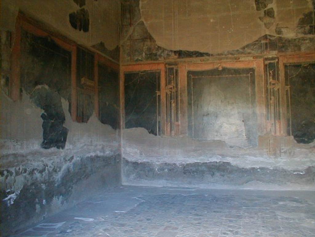 IV.21 Herculaneum, May 2004. Triclinium 5, with opus sectile floor, and 4th style wall decoration on black. Maiuri said, the spacious triclinium and drawing room, with its walls austerely painted from dado to cornice with sober architectural and ornamental motifs on a black ground broken by wide red bands, has on the other hand a dazzling floor of marble intarsia work (opus sectile), without any real geometrical design, being composed of so many separate tiles of varying shapes in different marbles. On the same side, there are a small room leading to the kitchen, the storeroom and the latrine, and a beautiful internal cubiculum with red walls and a floor in marble sectile; in the rear there is an elegant reception room (oecus) with the walls and the vault finely painted with a red background and a polychrome marble floor.
See Maiuri, Amedeo, (1977). Herculaneum. 7th English ed, of Guide books to the Museums Galleries and Monuments of Italy, No.53, (p.60-63).
