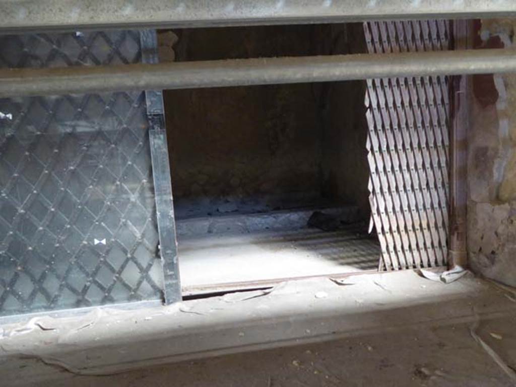 V.15 Herculaneum, September 2016. Detail of wooden sliding gate, separating the right (west) ala from the atrium.  Photo courtesy of Michael Binns.
According to Camardo and Notomista, an extraordinary carbonized wooden sliding gate was found in the right ala dividing it from the atrium, it was restored and left in situ. The gate was surmounted by a wooden cornice with a frieze in relief. On page 228 is a photo of the gate with detail of the wooden cornice with frieze. 
The photo was taken in the 1960�s and shows that the right-hand side of the screen was reconstructed with modern wood after the damage reported from the bombing in April 1943.
See Camardo, D, and Notomista, M, eds. (2017). Ercolano: 1927-1961. L�impresa archeologico di Amedeo Maiuri e l�esperimento della citta museo. Rome, L�Erma di Bretschneider, (p.227-8, Scheda 24).
