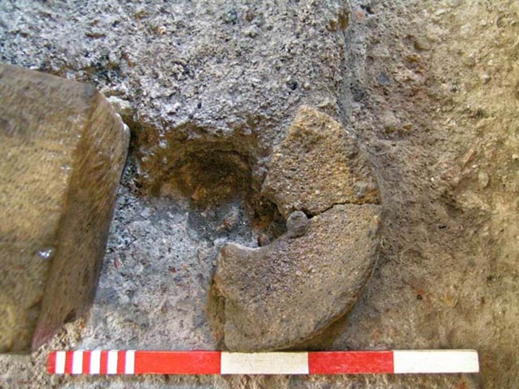 VI.12 Herculaneum. September 2004. Floor on west side of shop-room. Further excavation of circular stone lid or plate.
Photo courtesy of Nicolas Monteix.