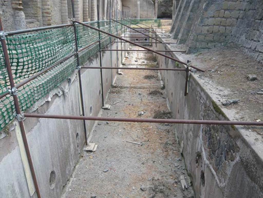 Ins. Orientalis II 4, Herculaneum, August 2013. Looking east along the long rectangular basin on the south side of the cryptoporticus. Photo courtesy of Buzz Ferebee.
According to Guidobaldi, - “
The long basin at the side of the cryptoporticus (a fish-breeding pond) was later eliminated and replaced by the large cross-shaped basin, which has only been partially excavated.” 
See Guidobaldi, M.P. (2009): Ercolano: guida agli scavi. Electa Napoli, (p.50) 

