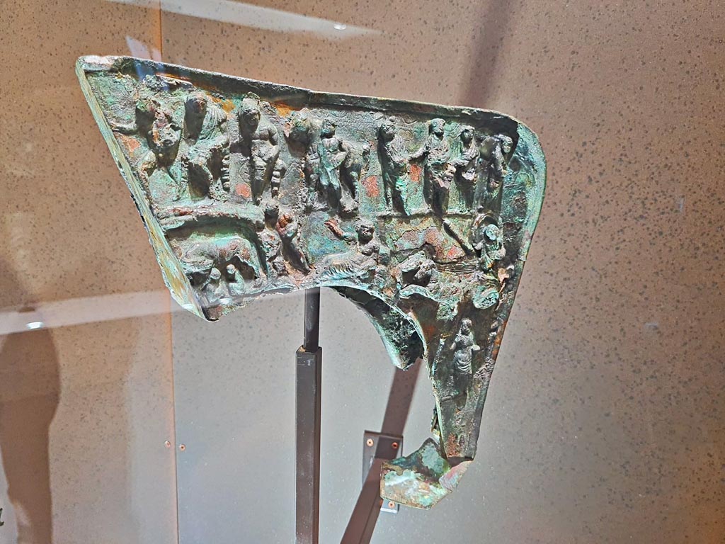 Found Herculaneum, 19th June 1834. Provenance unknown.
Bronze Mirmillo helmet crest with depictions of Mars, Rhea Silvia, she-wolf with Romulus and Remus and deities.
May 2021. On display in Naples Archaeological Museum, inventory number 5673-5656. Photo courtesy of Giuseppe Ciaramella.
According to the Museum card –
The crest, which is the only part of this type of helmet found at Herculaneum, has a depiction of Mars who appears in a dream to Rhea Silvia, the she-wolf with the twins Romulus and Remus, the chariot of Aurora and, above, Jupiter seated on a throne among other figures.
The inventory number is shown as 5673-5656.
