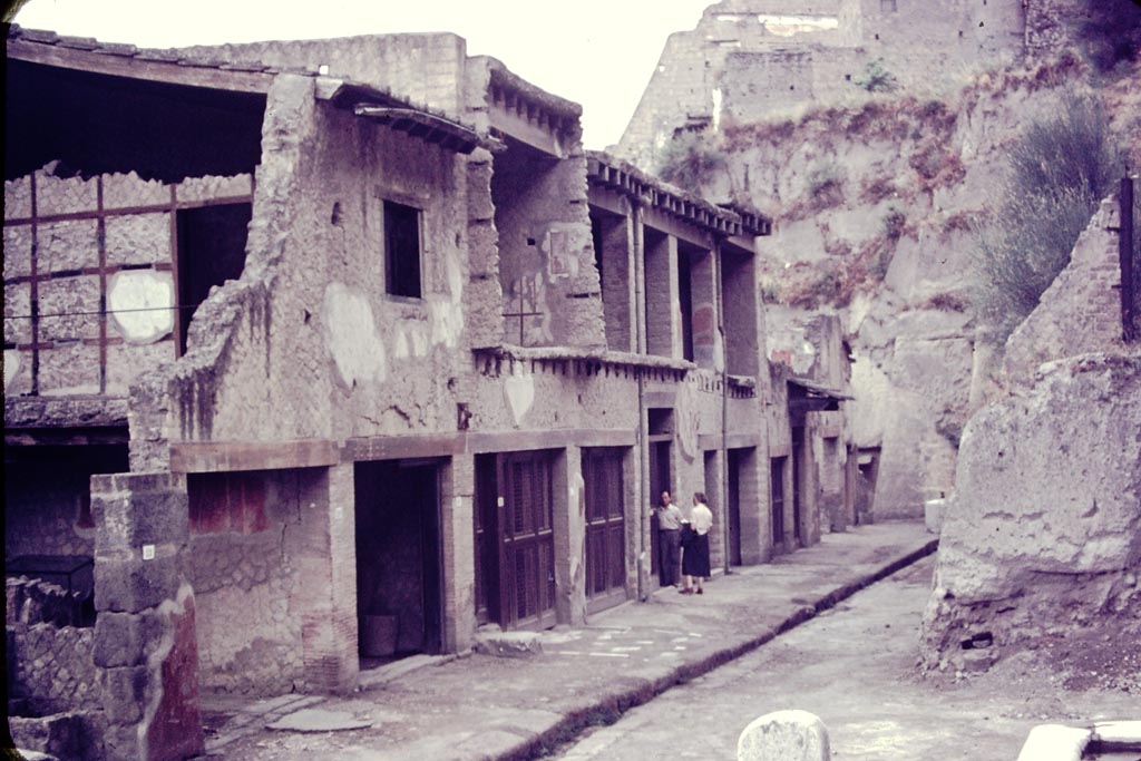 Insula V, north side, Herculaneum. 1955. 
Looking west along Ins V. on Decumanus Maximus, Wilhelmina is just going into V.15, the House of the Bicentenary. Photo by Stanley A. Jashemski.
Source: The Wilhelmina and Stanley A. Jashemski archive in the University of Maryland Library, Special Collections (See collection page) and made available under the Creative Commons Attribution-Non Commercial License v.4. See Licence and use details.
J55f0472.
